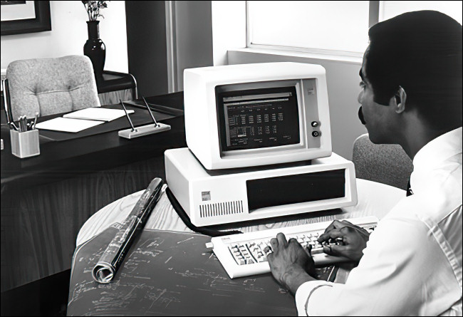 Un homme travaillant sur un IBM PC 5150.