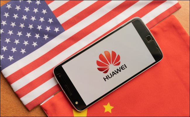 Telefon Huawei między flagą USA i Chin.