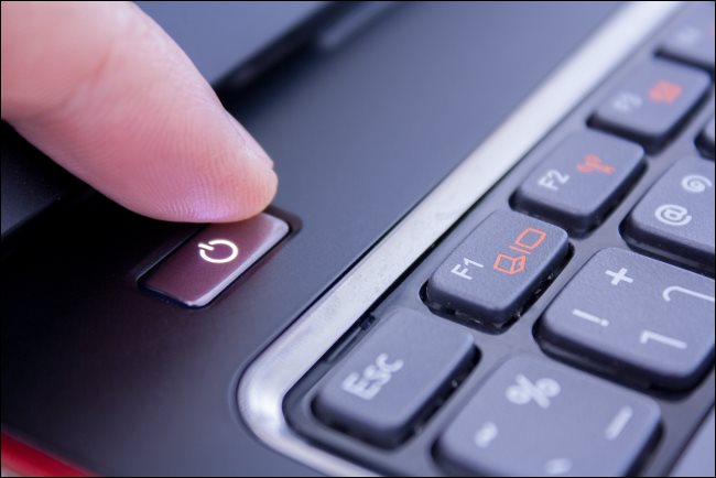 Palec naciskający przycisk zasilania laptopa PC, aby go wyłączyć.