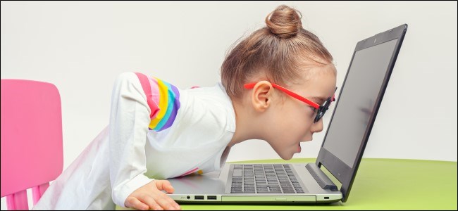 Ребенок в очках, прислонившись к ноутбуку