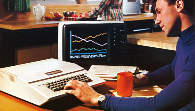A man at a desk typing on the very large Apple II keyboard in a 1977 advertisement.