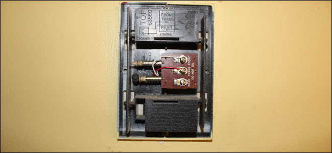 Una caja de timbre con cableado expuesto, un cable rojo en el terminal trans y blanco en el terminal frontal.