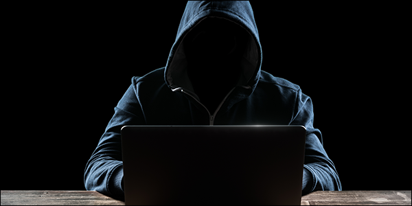 misterioso hombre nerd con una sudadera con capucha pirateando una computadora portátil
