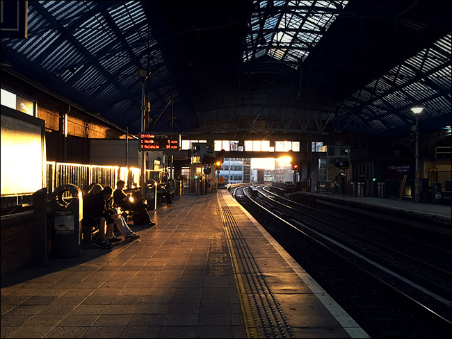 wnętrze dworca kolejowego z zachodzącym słońcem w tle